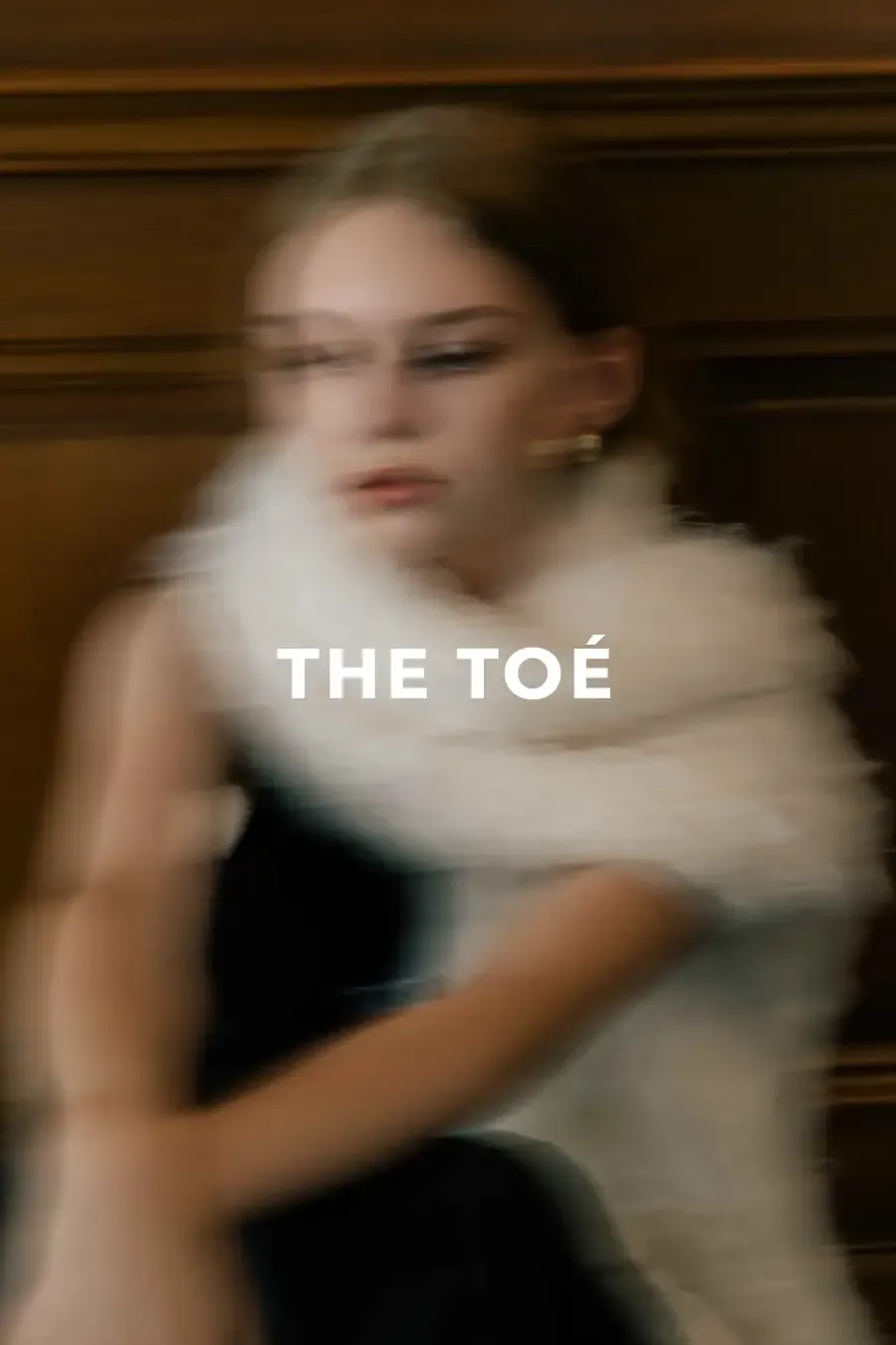 白いファーを纏うモデルとTHE TOÉロゴを捉えたモーションブラーのブランドビジュアル